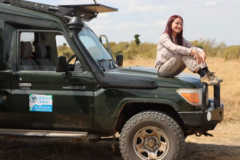 African safari hotel- a woman sits on our safari landcruiser and poses for a pic